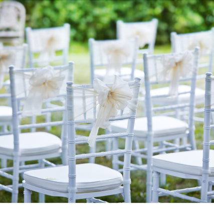 Wedding RentalsWhite wedding chairs set up outside on a clear day